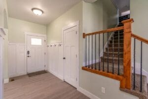 Freshly painted home entryway with sage green walls, white wainscoting, and trim near a wood staircase in Santa Rosa, CA