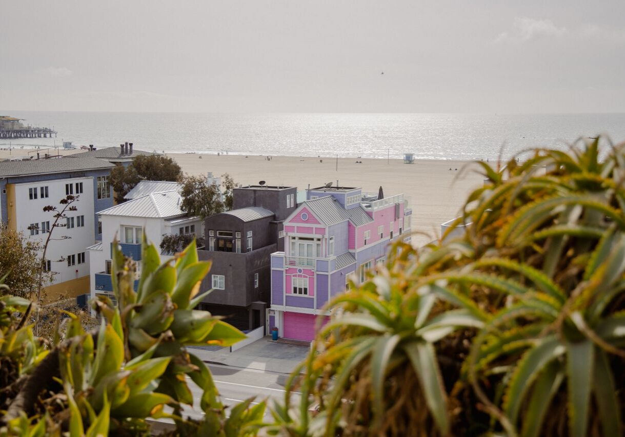 Row of colorful pink, purple, and blue beachfront homes with vibrant exterior paint along the California coast