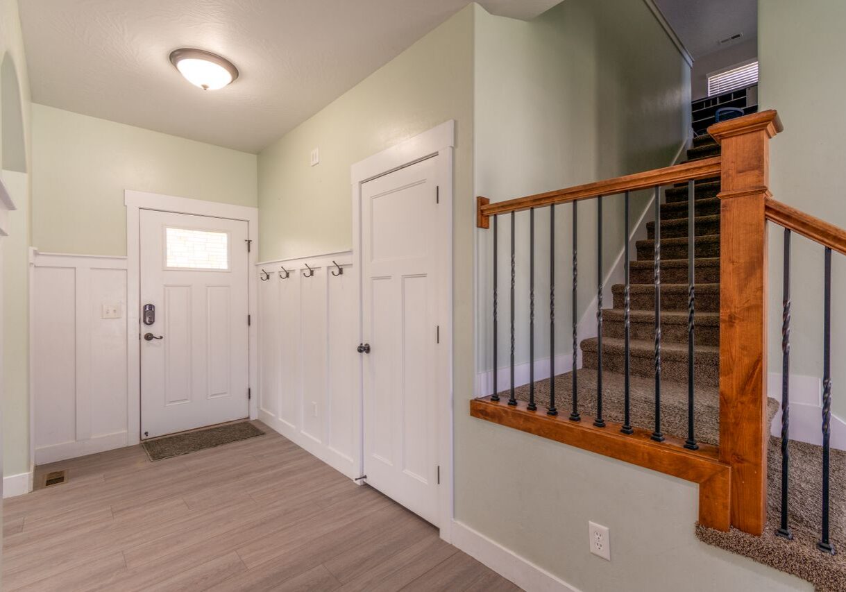 Freshly painted home entryway with sage green walls, white wainscoting, and trim near a wood staircase in Santa Rosa, CA