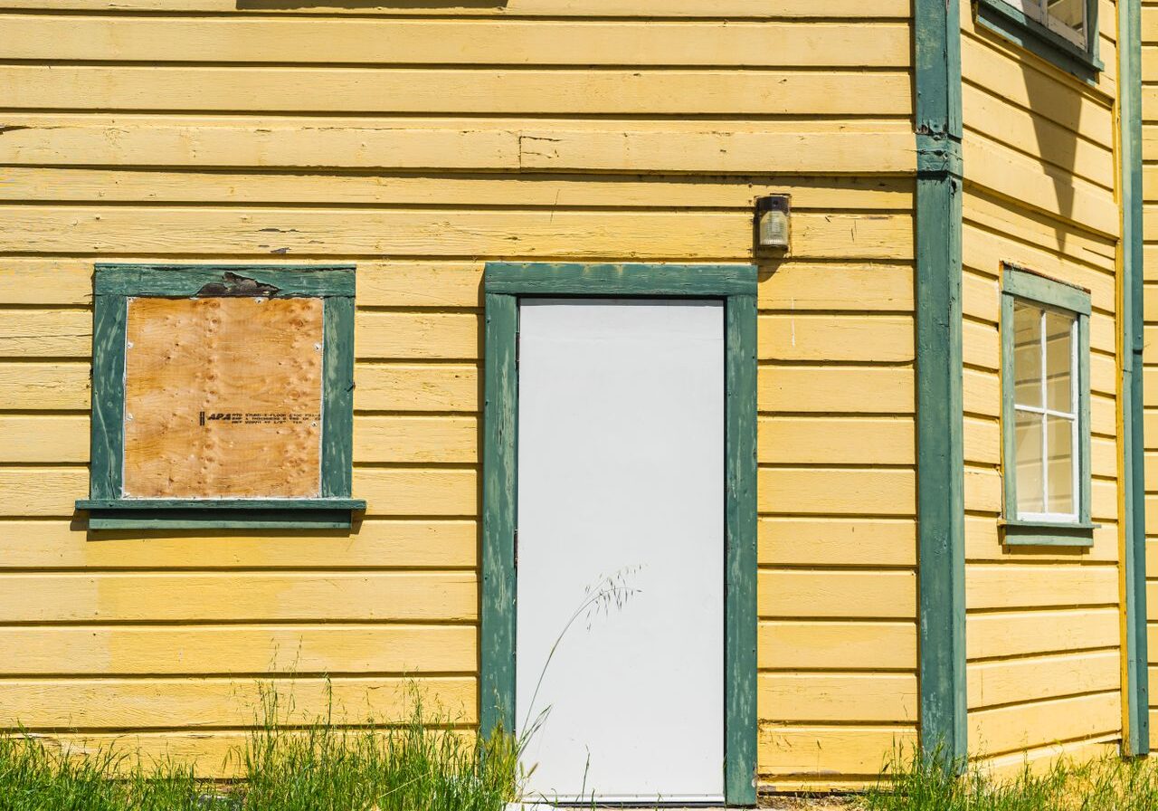 Yellow clapboard siding with green trim and a white door on a home exterior being prepped for repainting in Santa Rosa, CA